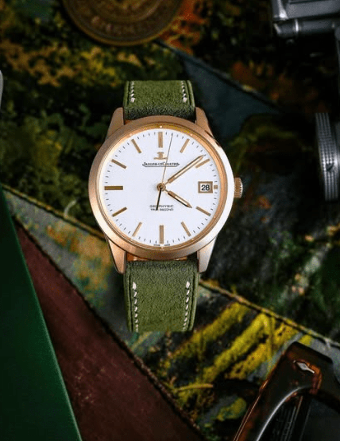 Rose gold watch with green leather strap on a textured surface