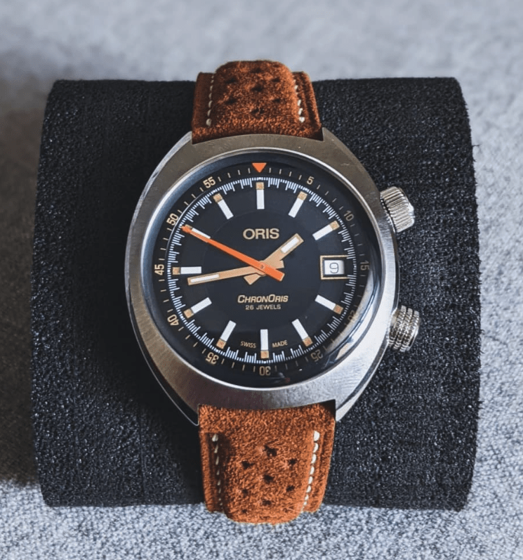 Oris watch with brown leather strap on a textured black stand