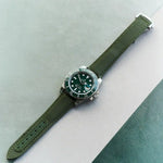 Watch with a green strap on a light gray and green background