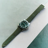 Watch with a green strap on a light gray and green background