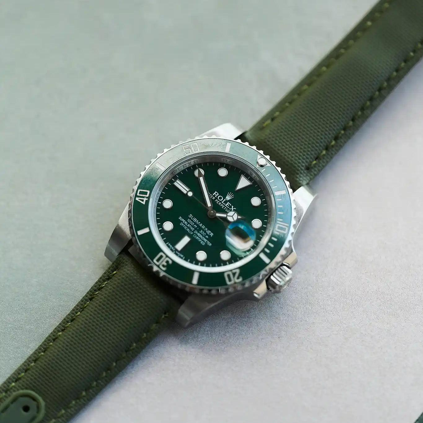 Watch with green strap and green dial on a light gray background