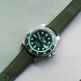 Watch with green strap and green dial on a light gray background