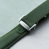 Green watch strap with silver buckle on a light gray background
